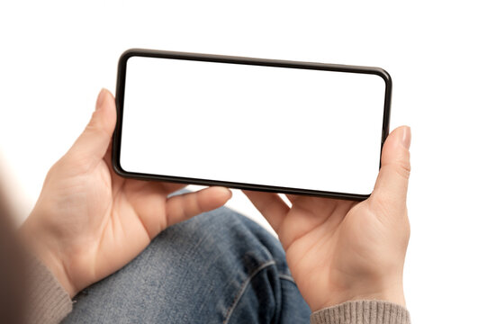 Woman Watching Video On Cell Phone Mockup Sitting On White Background. Mockup Phone Horizontal Position. Female Hands Holding Black Horizontal Mobile Phone