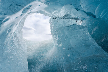Hole in ice cave against cloudy sky
