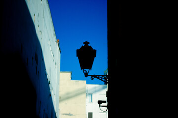 Fototapeta premium Beautiful victorian vintage lantern on the facade of an old European street, houses facades against blue clear sky. Postcard from a trip, travel to Spain, Madrid. Sunset in a town. Twilight cityscape.