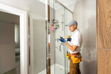 Young plumber fixing shower cabin