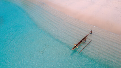 The boat is between the gradations of white sand and clean blue sea. Location in Pasir Purih Manokwari, West Papua Province