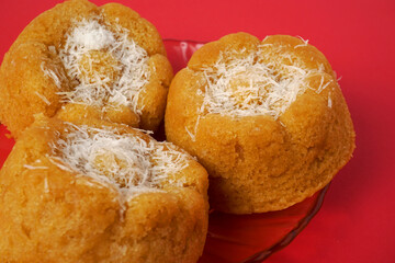 three apem cakes with a coconut topping on a red background  