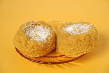two apem cakes with a sprinkle of coconut on a yellow background