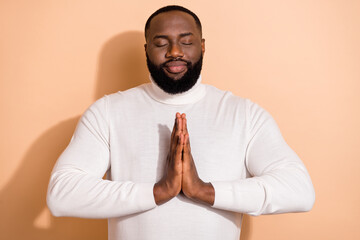 Photo of cute relaxed young guy dressed white pullover arms together practicing yoga isolated beige...