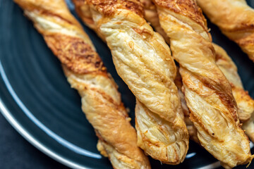 freshly baked, crispy, puff sticks on a round black plate. Perfect for a party.
