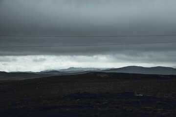 ROad trip in the center of the Island of Lewis and Harris in a moody, overcast gloomy and rainy day. Misty hills in the distance, electric lines and middle of nowhere felling.
