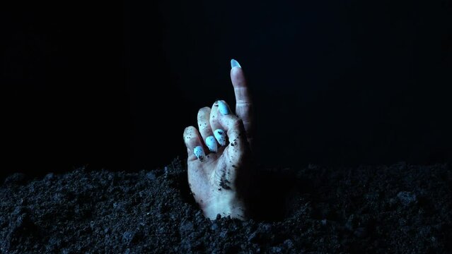 A zombie's hand sticking out of the ground is pointing at something.