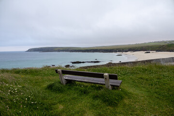 Wide angle view of Port Ness beach and a wooden bench in a looking point. Gloomy hebridean summer views.