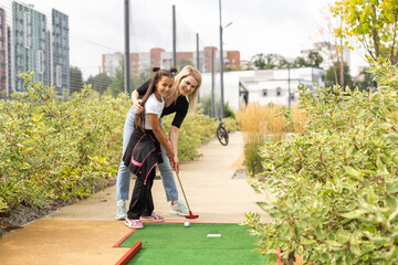 little girl and mother playing mini golf