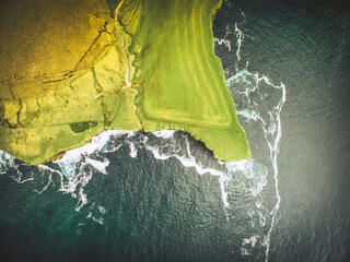 Dramatic aerial top down view scenic green cliffs with agriculture fields over ocean with scenic...