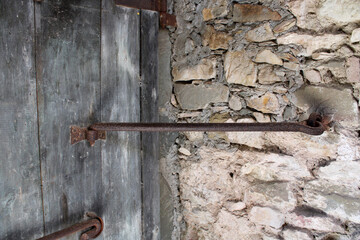 Antico ferro rugginoso di chiusura portone di legno con muro in pietra