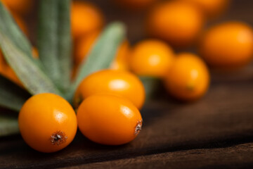 Buckthorn. Sea-buckthorn on wooden background. Buckthorn branch with leaves.