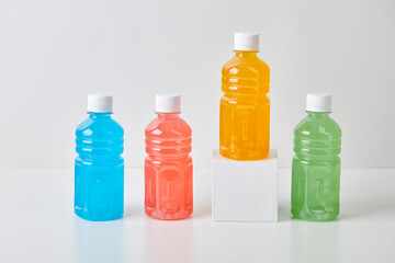 Four small bottles with colorful drinks on white background