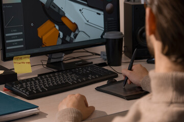 Caucasian male artist designer draws by stylus on tablet 3D models for games in office