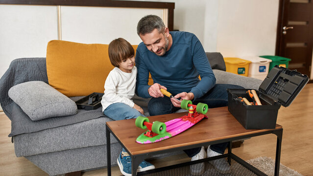 Dad Showing Little Son How Fixing Skateboard