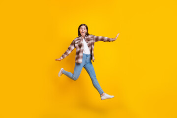 Fototapeta na wymiar Full length photo of adorable sweet lady wear checkered shirt jumping high smiling isolated yellow color background
