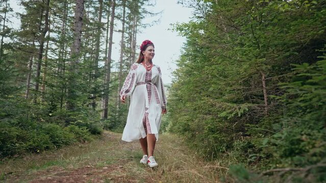 Ukrainian woman walking in fir forest, Carpathian mountains nature. Girl in traditional embroidery vyshyvanka dress. Ukraine, freedom, ethnic national costume