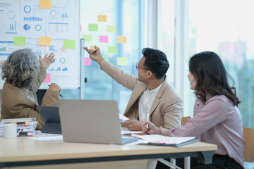 Group of Asian business people discuss together in team brainstorm meeting, work late night in office. Corporate business, coworker teamwork, financial consultant, or young entrepreneur concept