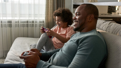 Black little son and father playing video game