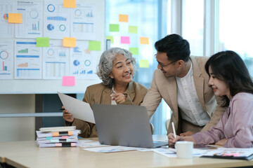 group of four happy young asian corporate executives working together meeting in office discussing business in office.