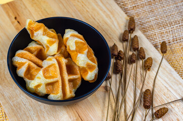 Delicious croissant waffle or croffle on black bowl on a wooden board, Waffles and Caffles concept, Dessert in cafe concept.