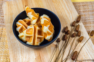 Delicious croissant waffle or croffle on black bowl on a wooden board, Waffles and Caffles concept, Dessert in cafe concept.