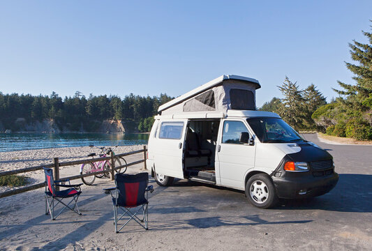 A camper van parked in a cove on Cape Arago on the Oregon coast., camping chairs and bicycles.
