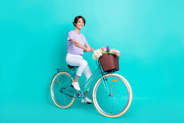 Full length photo of funny cute girl dressed purple t-shirt riding bicycle isolated teal color...