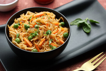 Schezwan Noodles or vegetable Hakka Noodles or chow mein, served in a bowl or plate with tomato sauce, ketchup, wooden chopsticks, India. popular Indo-Chinese Indian Maggi noodles. - obrazy, fototapety, plakaty