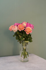 Bouquet of roses on a gray table on a green background.