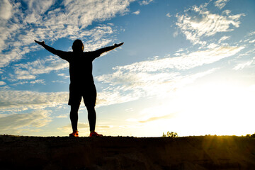 Silhouette of a man happily spreading his arms.