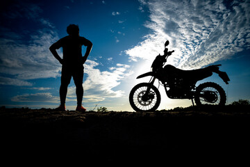 Fototapeta na wymiar Silhouette Man enjoying a motocross bike on a beautiful evening in the mountains.