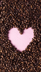 Coffee background made of beans with a pink heart laid out