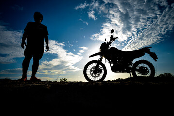 Plakat Silhouette Man enjoying a motocross bike on a beautiful evening in the mountains.