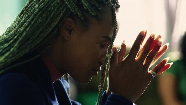 Spiritual African American Praying To God. A Religious Black Hispanic Latina Adult Girl In Prayer Profile Closeup Face. Person Worships To Divinity