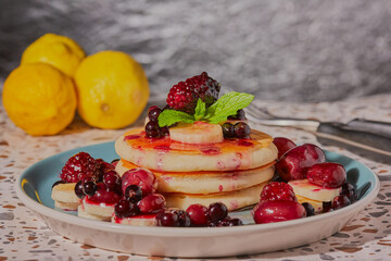 Pancakes with mixed fruit and honey and garnished with mint.