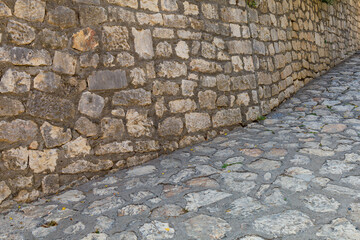 Stone wall and stone road or sidewalk in the architecture of the old town. Background or backdrop