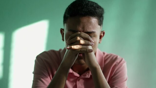 Religious hispanic young man praying to God in transcendence. South American Brazilian person in prayer looking at sky with HOPE and FAITH