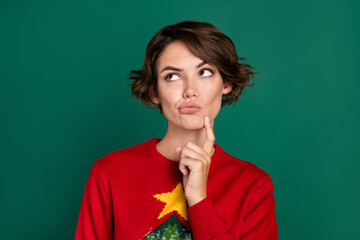 Photo of minded lady printed jumper finger touch face look empty space choose xmas outfit present isolated on green color background