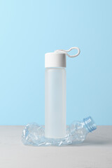 No plastic, Zero Waste, Sustainable Lifestyle. Choice Plastic Free Items alternative to disposable. Crumpled plastic bottle and glass bottle on pastel blue background.