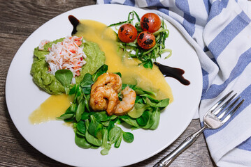 Salad with crab, cucumber, cocktail shrimp, avocado tartar and mango sauce. View from slightly above. Fresh and juicy foods. Homemade mouthwatering food.