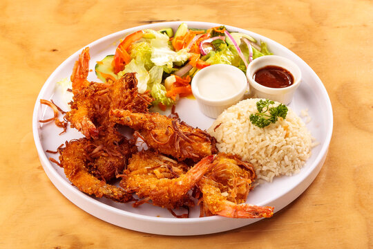 Fried shrimp breaded with coconut, sweet sauce, salad and rice, food, gastronomy