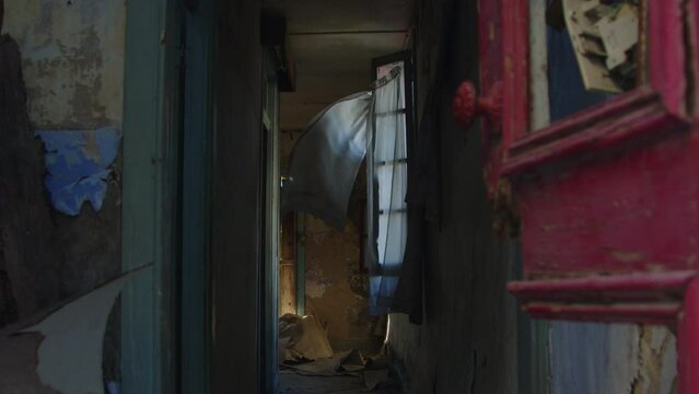 Curtains flutter on the wind in old abandoned house, damaged wall and furniture, nostalgic feeling, Slow motion.
