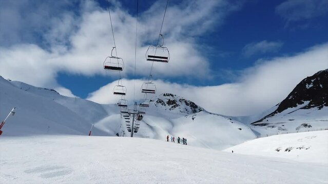 view of snow-capped mountains with moving chairlift and a small group of unrecognizable skiers