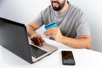 Unrecognizable young man with computer and holding card to shop online from home - concept shopping, black friday, cyber monday, sales, christmas