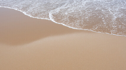 Fototapeta na wymiar sea foam breaking on a golden sandy beach