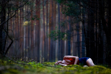 beautiful long-haired woman rests on soft moss in a mysterious forest; lying on moss; magical forest at suns