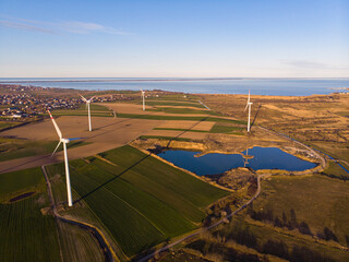 drone photography of the sunset over a wind farm with a view of the sea and a peninsula in the background; green energy