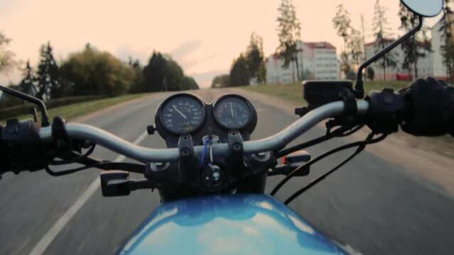 motorcycle ride on asphalt road at sunset. Hands and steering wheel.