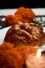 Bread of the dead with cempasuchil flowers, candles around and placed with confetti with dia de muertos shapes